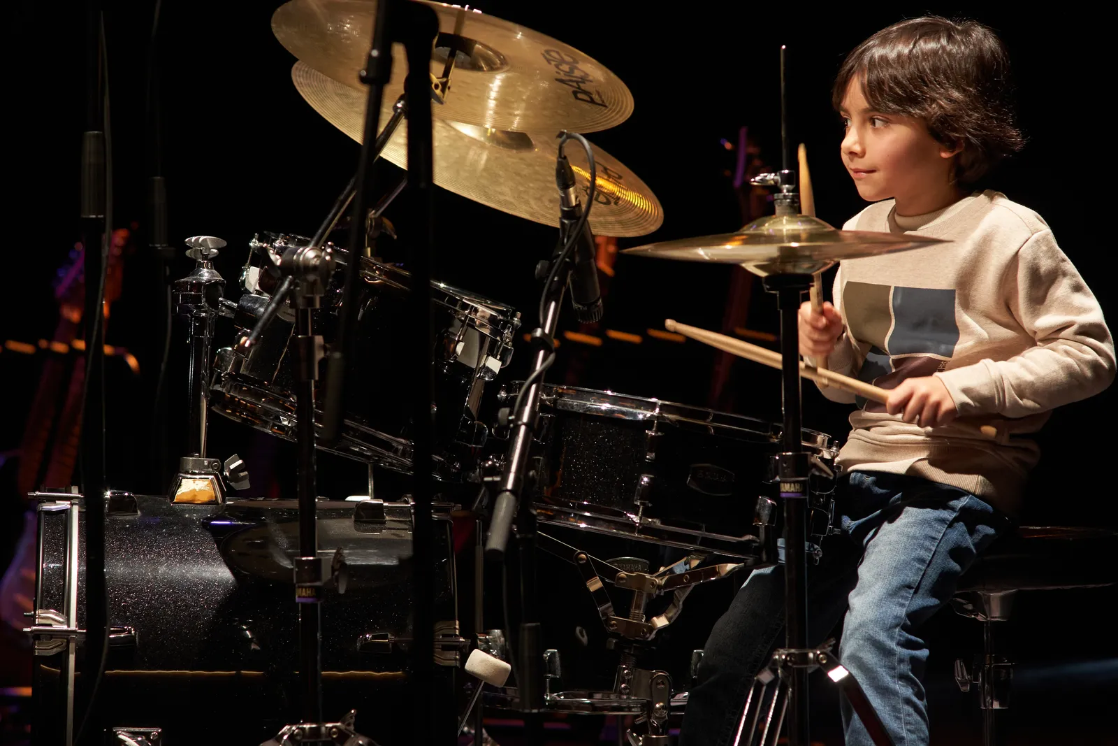 Jovem baterista a tocar em palco num recital d'Os Músicos