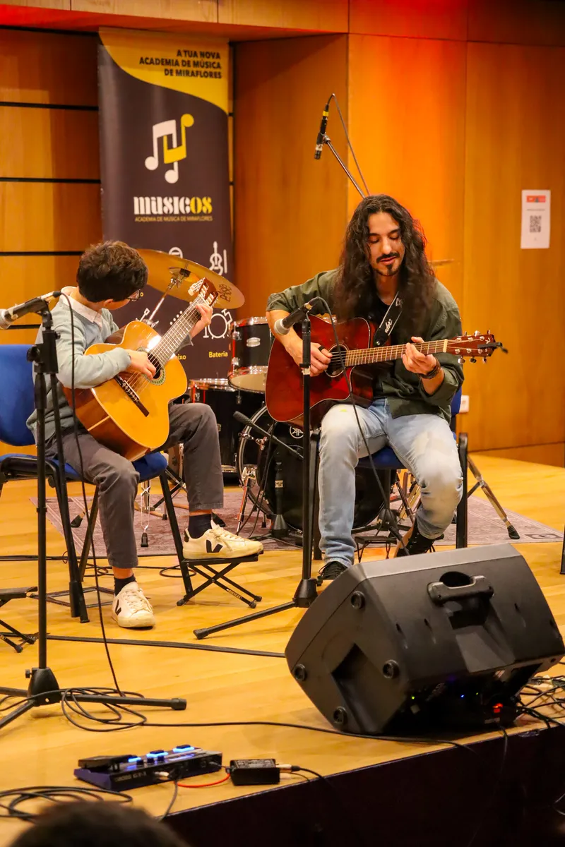Banda de alunos em palco com público em silhueta